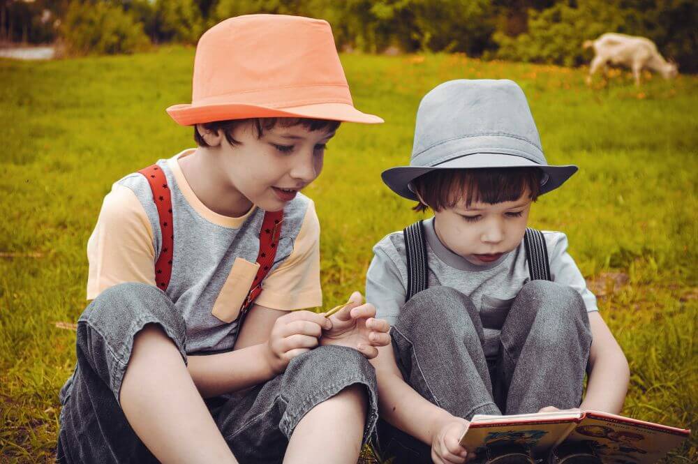 dzieci czytające książkę na łące